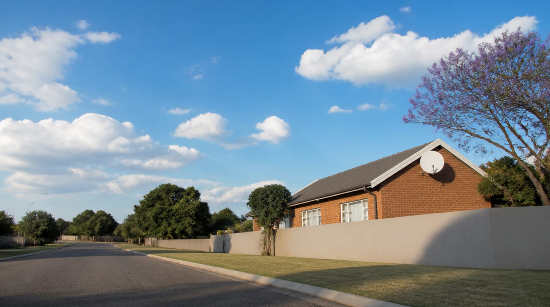 Satellite dish mounted on the face-brick gable of a suburban home
