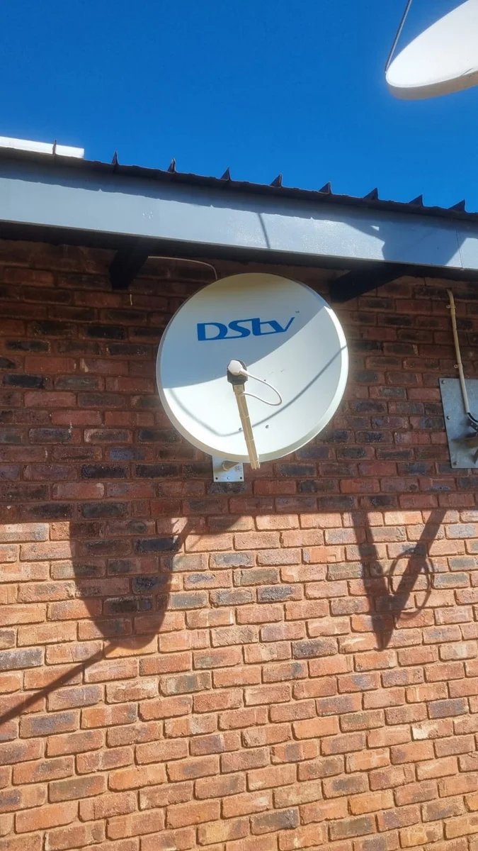 Satellite dish on a brick wall being checked after a loss of signal