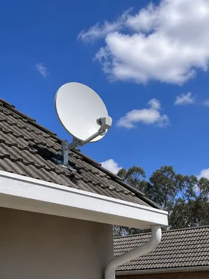 Satellite dish mounted at the edge of a concrete-tile roof