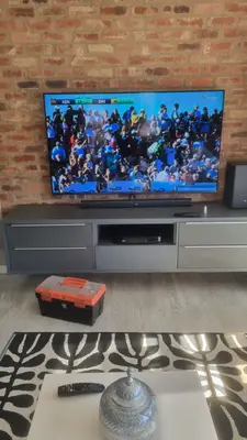 TV wall mount with soundbar and decoder showing live sport